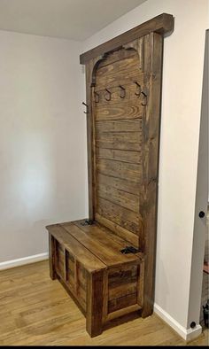 a wooden bench sitting inside of a room next to a white wall and wood floor