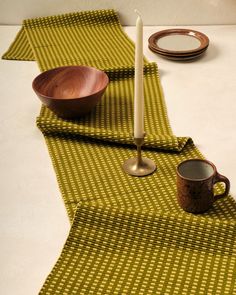 a table topped with plates and bowls on top of a white table cloth next to a candle