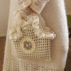 a close up of a handbag on a person's arm wearing a white sweater