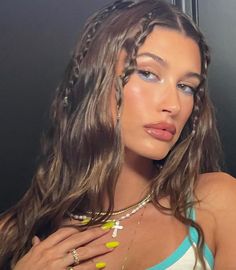 a woman with braids on her hair and blue eyeshadow is posing in front of a mirror