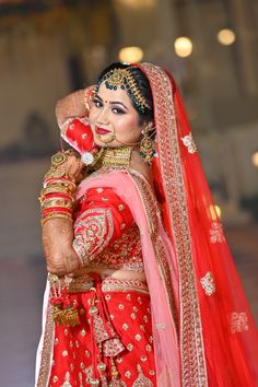 a woman in red and gold bridal outfit with her hands on her head, posing for the camera