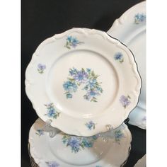 three plates with blue flowers on them sitting next to each other in front of a black background