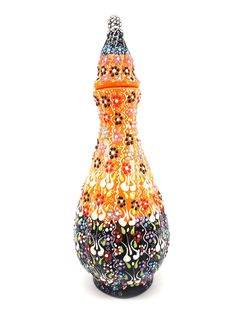 a multicolored vase is sitting on a white surface with an orange top and black bottom