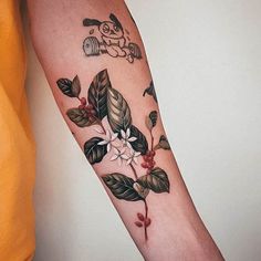 a woman's arm with flowers and leaves tattooed on the left side of her arm