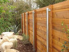 a wooden fence with metal posts and rocks