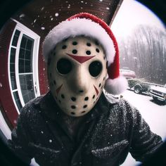 a man wearing a mask and santa hat in the snow with a house behind him