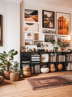 a living room filled with lots of pictures and plants on the wall next to bookshelves