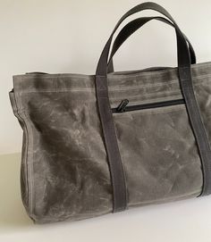 This extra-large 13.5 oz waxed canvas tote is rugged and spacious. My original design is unique and stylish. The rounded bottom provides extra space for bulky items.  There's a large interior zippered pocket and an exterior zippered pocket. 10.10 oz Army Duck Canvas is treated with 3.5 oz of wax and is heavier than most waxed canvas bag fabrics.  Army Duck is tightly woven and very strong.   The bag is 18" wide x 10" deep, sides are 13" high. Zippered pocket inside measures 16" x 7". Outside poc Wax Canvas Bag, Rectangular Waxed Canvas Weekender Bag With Large Capacity, Large Capacity Waxed Canvas Duffle Bag, Large Capacity Rectangular Waxed Canvas Duffle Bag, Casual Weekender Bag With Waxed Finish, Practical Duck Canvas Bag For Everyday Use, Waxed Canvas Bag With Pockets For Daily Use, Waxed Canvas Bag For Daily Use, Large Capacity Waxed Canvas Tote Bag