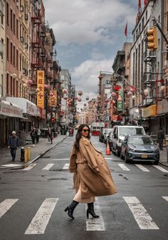 a woman crossing the street at an intersection in a city with tall buildings and cars