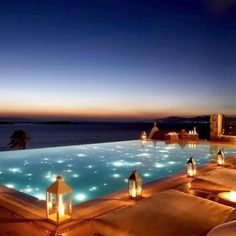 an outdoor pool lit up with candles and lanterns