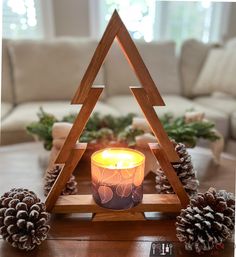 a candle sitting on top of a table next to pine cones