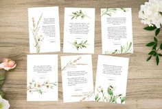 four cards with watercolor flowers on them sitting next to a bouquet of white flowers