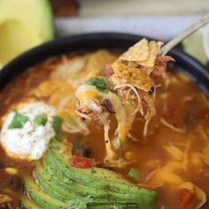 a spoonful of mexican soup with tortilla chips and avocado