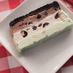 a piece of ice cream cake on a white plate with a red checkered tablecloth