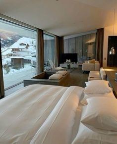 a large bed sitting next to a living room filled with furniture and windows covered in snow