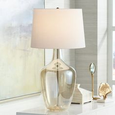 a table with a lamp on top of it next to a painting and other items