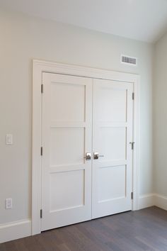 an empty room with two white doors and hard wood flooring on the side wall