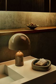 a table lamp sitting on top of a white counter next to a bowl of food