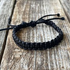 a black string bracelet sitting on top of a wooden table