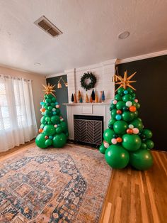 two green christmas trees sitting on top of a wooden floor next to a fire place