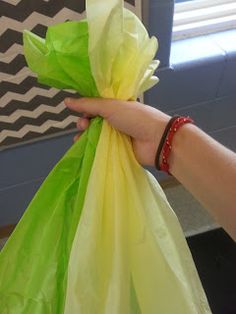 a hand holding a green and yellow bag with something in it's left hand