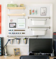 a desk with a computer monitor, keyboard and speakers on it in front of a pegboard wall