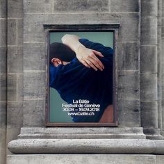 a poster on the side of a building with a person's hand touching it