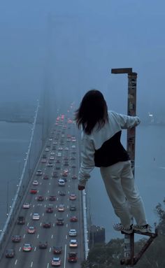 a person standing on a ladder in the middle of a highway with cars driving down it