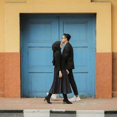 two people are walking past a blue door