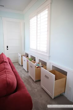 a living room with red couches and boxes on the floor in front of it