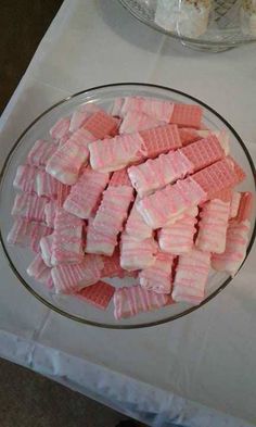 pink and white marshmallows in a glass bowl on a table with other desserts