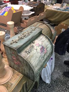 an old wooden box sitting on top of a table next to other boxes and chairs