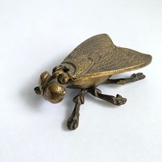 a gold colored insect figurine sitting on top of a white surface