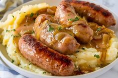 two sausages and mashed potatoes in a white bowl on a blue table cloth