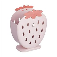 a white and pink strawberry shaped object with holes in the center, on a stand