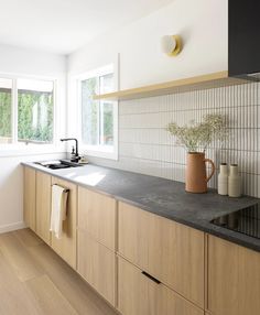 a kitchen with wooden cabinets and black counter tops next to a white tiled backsplash