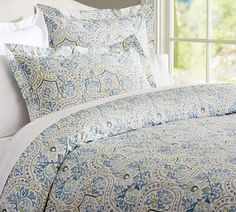 the comforter is made up with blue and green paisley designs on it, along with white pillows