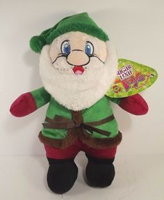 a stuffed toy with a green and red outfit on it's head, holding a candy bar