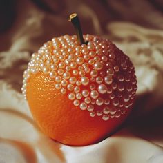 an orange with pearls on it is sitting on a bed sheet and looks like something out of space