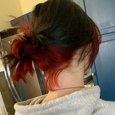 the back of a woman's head with red hair in a messy bun, looking into an oven