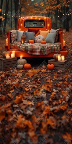 an orange truck bed with candles on it in the middle of leaves and pumpkins