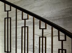 a stair case with metal handrails in front of a stone wall and floor