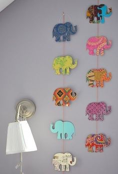 an elephant themed mobile hangs on the wall next to a lamp in a child's room