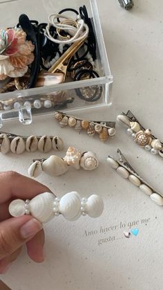 a person is holding some seashells in their hand and there are other sea shells on the table