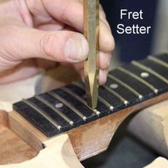 a person is using a pair of scissors to cut something out of a piece of wood