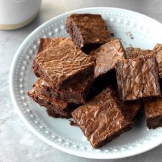 a white plate topped with brownies on top of a table next to a cup