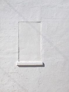 a white wall with a square window on it