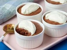 four dessert cups with white frosting and chocolate pudding in them on a pink tray