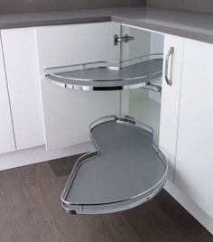 a corner shelf in the middle of a kitchen with white cupboards and wood flooring