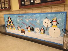 a bulletin board with penguins and snowmen on it in the lobby at a school